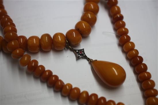 A single strand graduated disc shaped amber bead necklace with rose cut diamond and ruby set amber drop pendant, gross weight